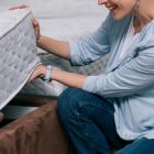 cropped shot of smiling woman choosing orthopedic mattress in furniture store